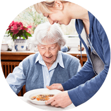 Photo of a woman setting down a bowl of soup in front of a senior woman at a table