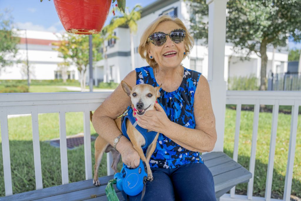 Female resident sitting on bench with a small dog at Alamar Senior Living