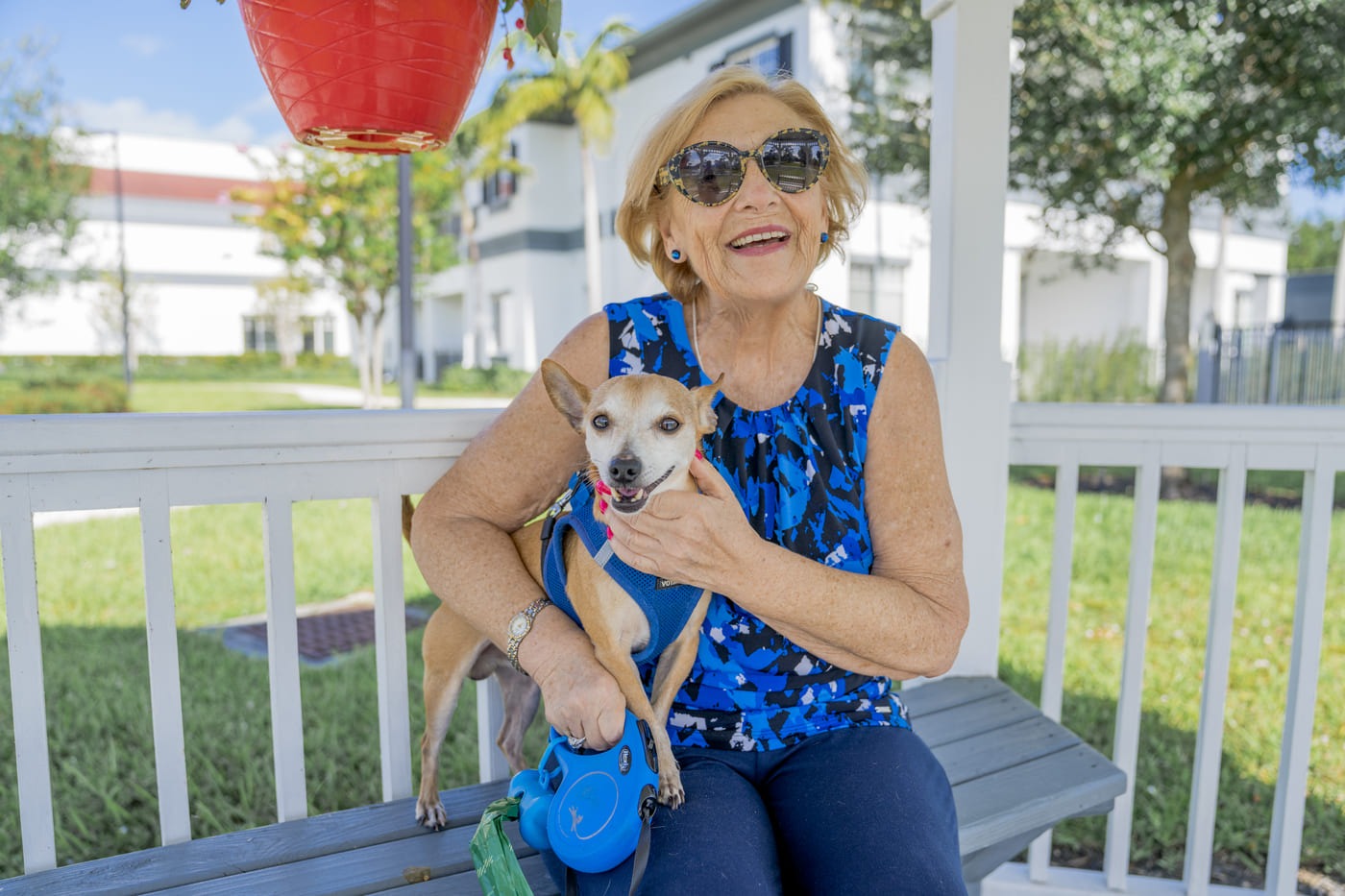 Female resident sitting on bench with a small dog at Alamar Senior Living