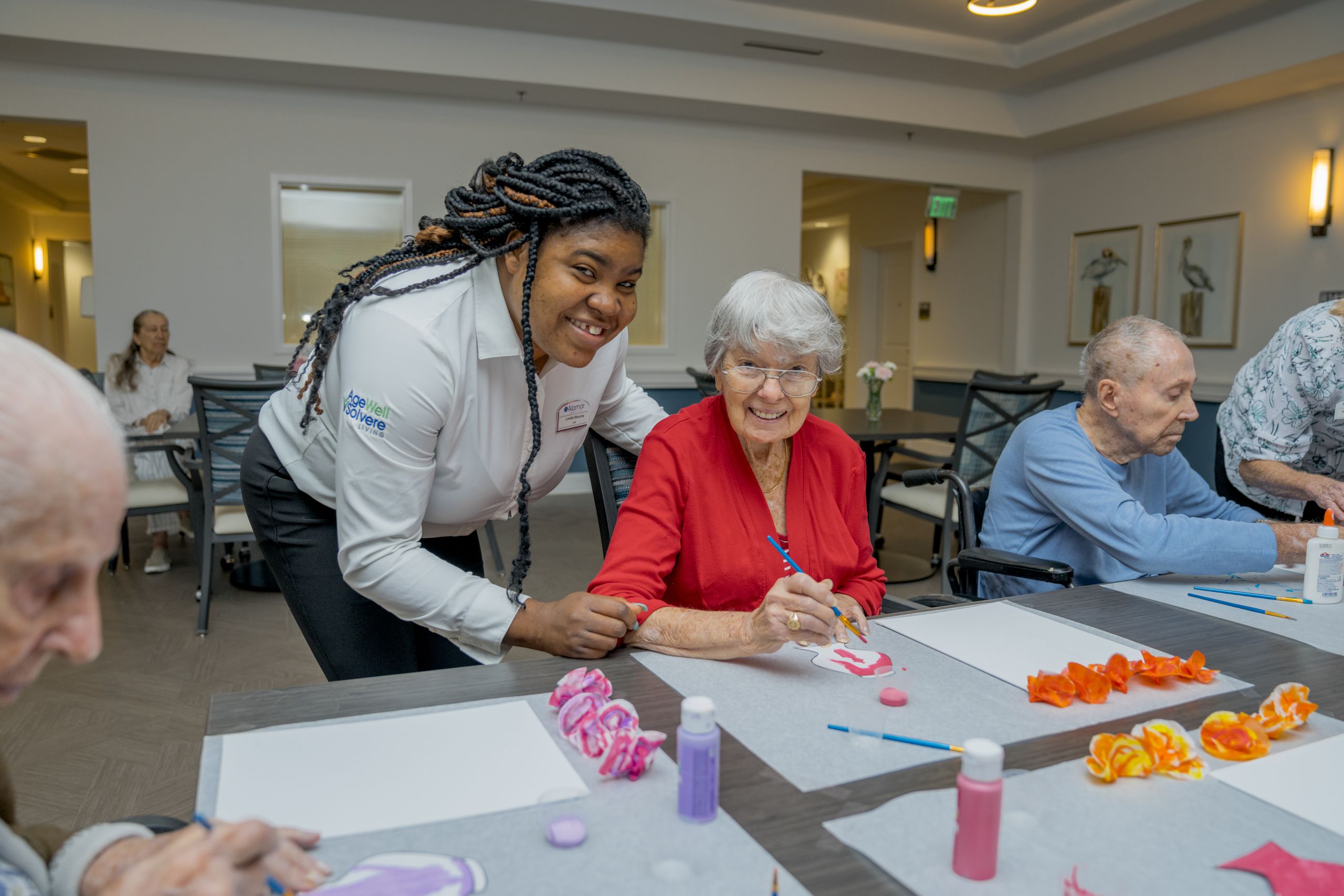 Resident of Alamar Senior Living engaging in an enriching activity with the help of a team member.