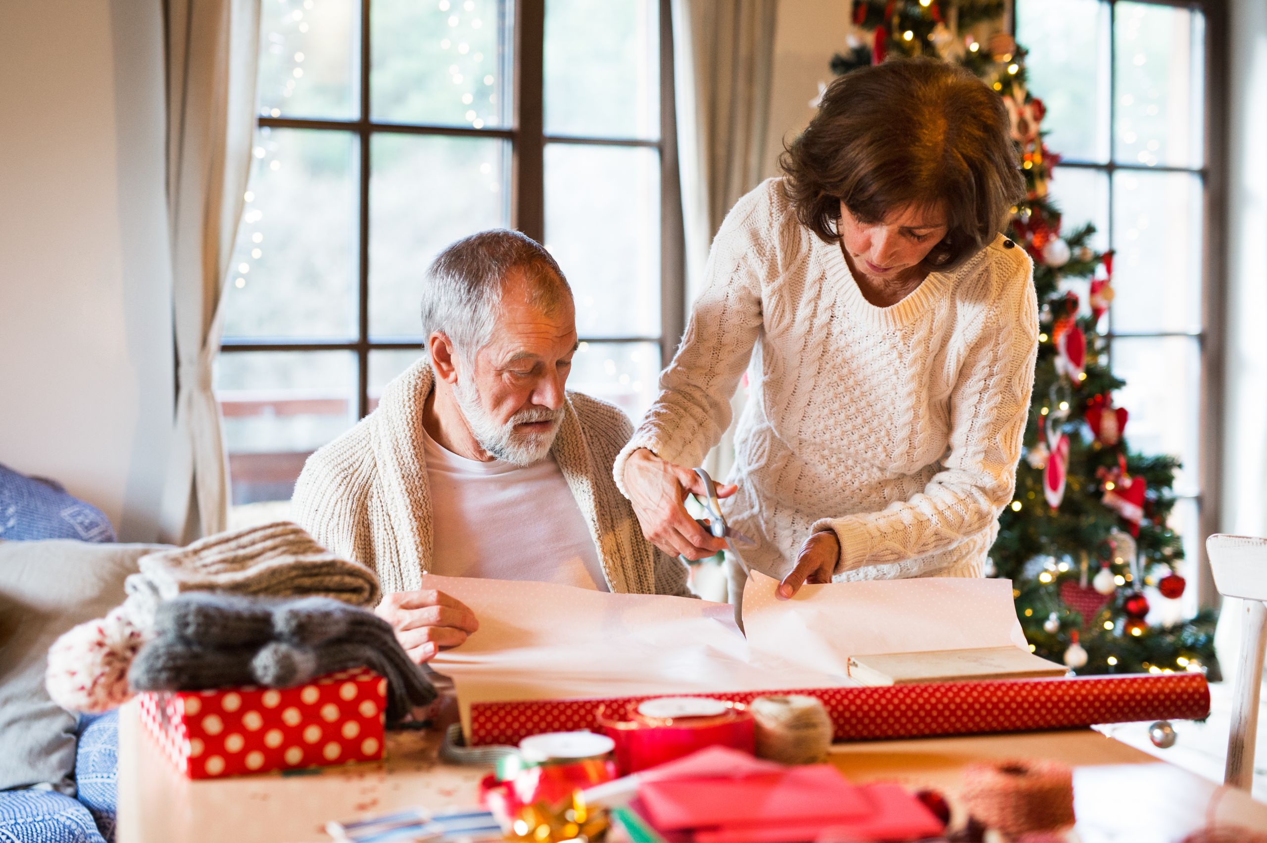 A team member at Alamar Senior Living helps an older man wrap gifts 